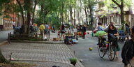 Auf der Straße spielen Kinder und malen mit Kreide. Bälle und Spielzeug liegen auf dem Boden.