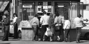 Menschen stehen 1990 vor einem Rostocker Zeitungskiosk in der Schlange - schwarz-weiss Aufnahme