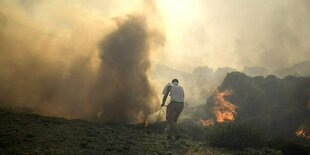 Ein Mann versucht mit einer Schaufel das Feuer zu löschen