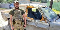 Ein Soldat der 5. Slobozhanka-Brigade steht vor einem zerschossenen Auto
