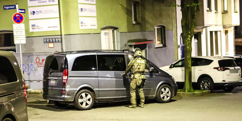 Polizist steht nachts vor einem Auto, das in deiner Straße parkt