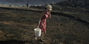 Eine Frau trägt Wasser in einem Eimer während eines Feuers