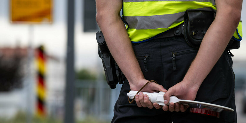 Ein Polizist mit Haltekelle in den Händen steht an der deutsch-polnischen Grenze