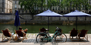 Menschen sitzen in Sonnenliegen am Fluss