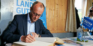 Friedrich Merz trägt sich während eines Wahlkampfauftritts des CSU Kreisverband Rosenheim-Land in einer Festhalle in ein Gästebuch ein.
