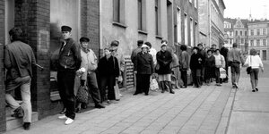 Schwarz-weiß-Aufnahme von Menschen die vor einer Bäckerei warten