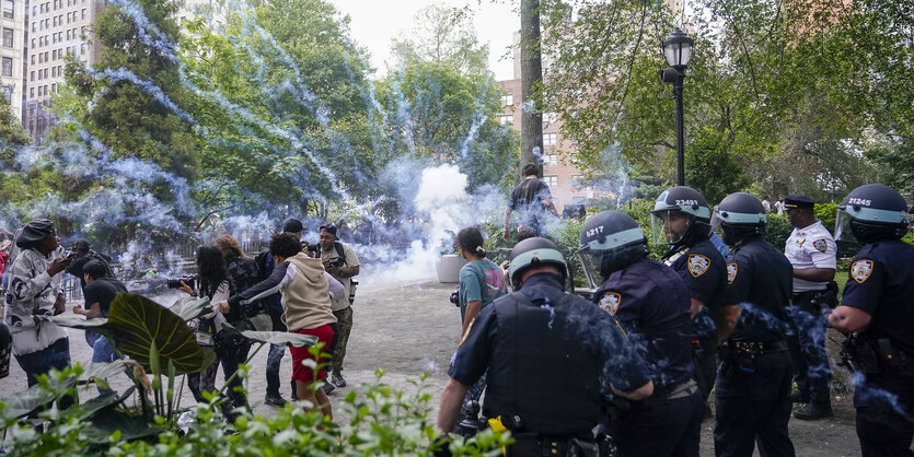 Polizist*innen und Jugendliche stehen in Gruppen inmitten einer chaotischen Situation auf dem Union Suare. Im Hintergrund steigt Rauch auf