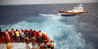 Migranten an Bord des Rettungsbootes der NGO Proactiva Open Arms Uno blicken auf das Boot der Guardia Costiera, das auf dem Weg zur Insel Lampedusa ist