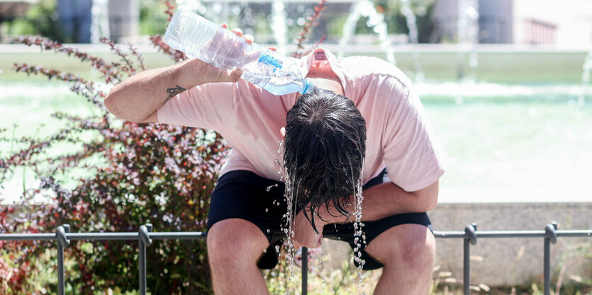 Eine Mann kühlt sich mit Wasser ab