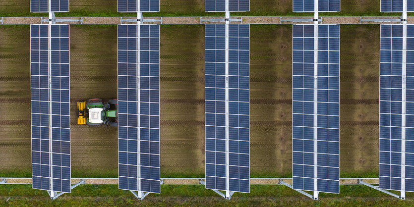 Ein Traktor fährt unter Solarpanelen