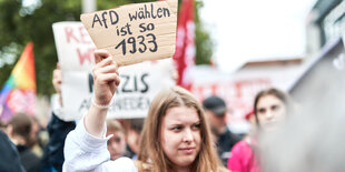 Eine Frau hält ein Plakat hoch worauf steht "Afd wählen ist so 1933"