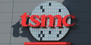 Logo der Chipfabrik tsmc hängt rot an einem Gebäude, eine Kugel mit ausgesparten schawrzen Flächen