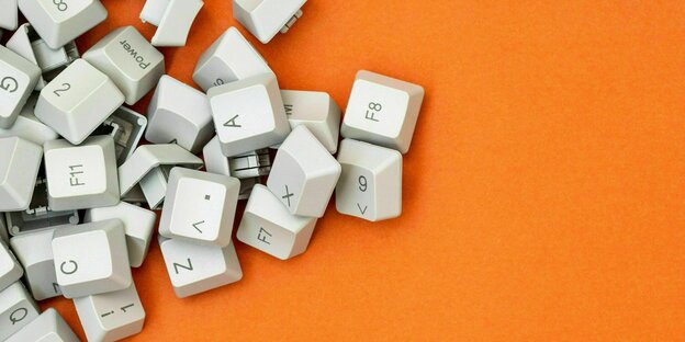 Einzelteile einer Tastatur liegen auf einem orangefarbenen Hintergrund