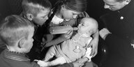 historische Aufnahme eines Säuglings umringt von Kindern und einem Mann in Nazi-Uniform