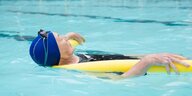 Eine ältere Frau schwimmt in einem Pool mit einem Schwimmreifen