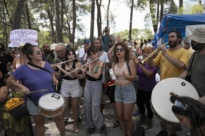 Musizierende Demonstrant:innen in einem Wald.