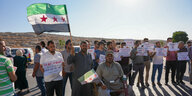 Menschen protestieren mit einer syrischen Revolutionsfahne