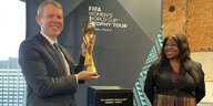 Neuseelands Premier Chris Hipkins hä#lt den Weltpokalmin Händen, Fifa-Generalsekretärin Fatma Samoura schaut zu