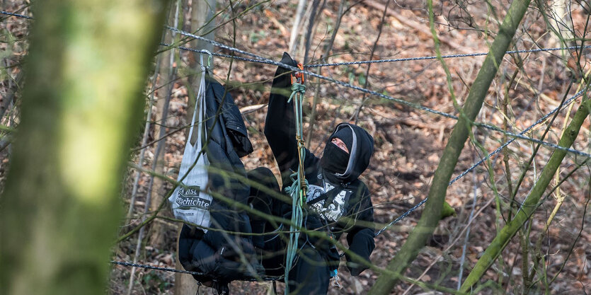 Ein vermummter Mensch in einem Wald