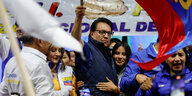 Ein Mann steht zwischen anderen Menschen und schwenkt Ecuadors Fahne