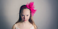 Eine junge Frau mit rosa Schleife im Haar schaut in die Kamera
