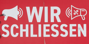 Ein Schild auf dem "Wir schliessen" steht, in einem Schaufenster.