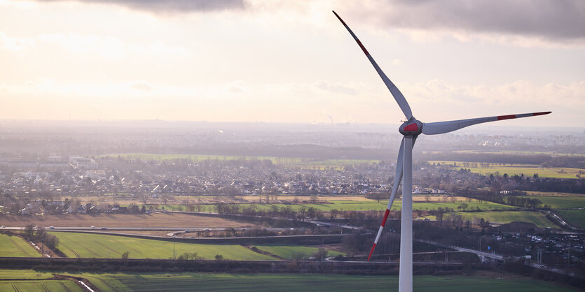 Windrad vor Stadtlandschaft und Himmel