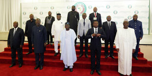 Auf einer Treppe mit feierlich rotem Teppich stehen 14 Männer, im Hintergrund ist das Logo der Ecowas zu sehen