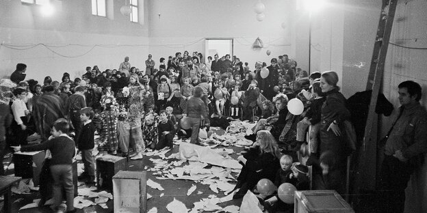 Schwarz-weiß-Aufnahme vom Münchener Kunstvereins bei einer Vollversammlung, der Raum mit unter anderem Kindern und Eltern, ist ganz voll und chaotisch