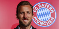 Der Fußball-Star Harry Kane steht vor einem Bayern München Logo