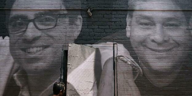 Gesichter zweier zu Unrecht vom iranischen Regime Inhaftierter sind auf eine Mauer gemalt