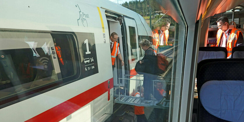 Fahrgäste eines liegengebliebenen ICE steigen über einen Steg in einen anderen Zug um.