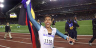 Cathy Freeman jubelt mit einer Fahne nach einem Rennen in einem vollen Stadion.