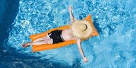 Eine Person mit Strohhut auf einer Luftmatratze im Pool.