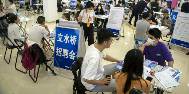 Junge Chinesen sitzen an Tischen