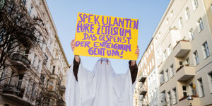Eine Aktivistin im Gespensterkostüm hält ein Schild hoch auf dem steht: «Spekulanten eure Zeit ist im, das Gespenst der Enteignung geht um!»