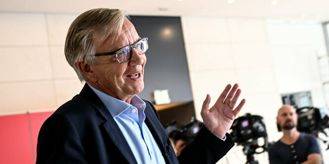 Ein Mann im Anzug (Dietmar Bartsch) von den Linken gestikuliert bei einer Pressekonferenz.