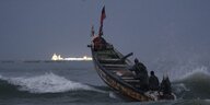 Ein Fischerboot auf dem Wasser vor Senegals Küste. Im Hintergrund sieht man die Lichter des Gasterminals.