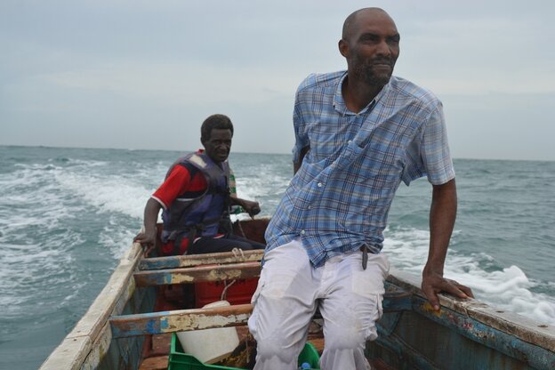 O pescador Mame Moussé Ndiaye e outro homem num barco de pesca no mar.