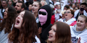 Protestierende mit weiß-roten Fahnen und mit einer rosa Sturmmütze