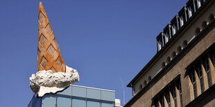 Überdimesionale Eistüte des Künstlers Claes oldenburg auf einem Hausdach.