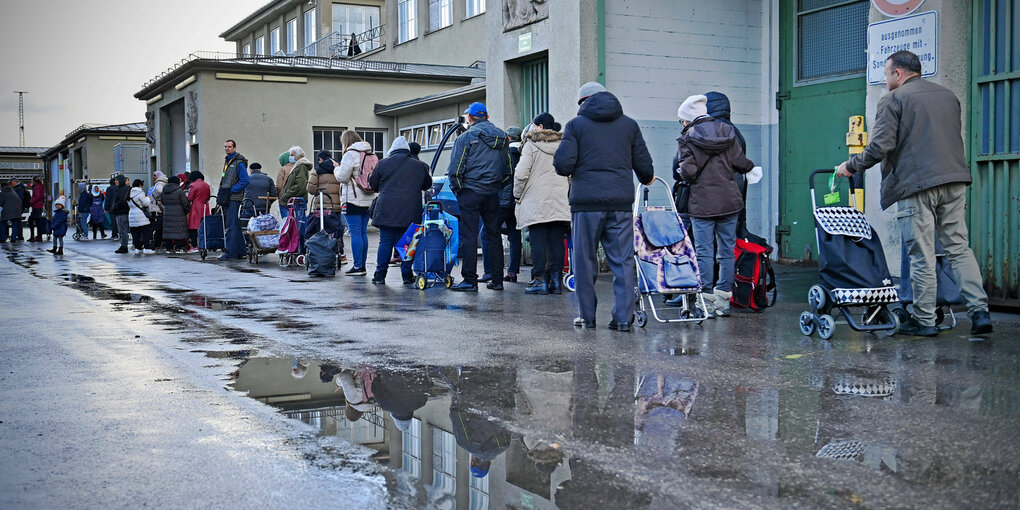 Menschen mit Einkaufswagen stehen Schlange.