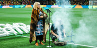 Eine indigene australische Frau steht im Fußballstadion von Melbourne und spricht in ein Mikrofon