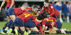 Spaniens Spielerinnen liegen in einer Traube übereinander auf dem Rasen und jubeln