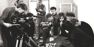 Schwarz-weiß-Aufnahme von einem Filmdreh. Der Kameramann Sebastian Richter schaut in seine Kamera. Rechts im Bild sitzen jegendliche Punks. Auf dem Rücker der Lederjacke der Person ganz vorne im Bild ist das Wort "Jetzt" zu lesen.