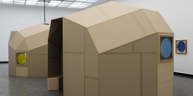 Zwei von Oscar Tuazons aus Karton gefertigten polygonalen Pavillions stehen in einem Ausstellungsraum.
