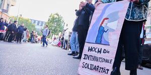 Demonstrant*innen stehen in einer Menschenkette und halten ein Plakat mit der Aufschrift „Hoch die internationale Solidarität“