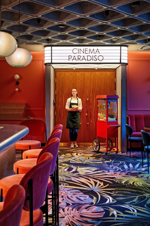 Eine Frau steht vor dem Eingang eines Kinos im Hotel Puro. Über dem Eingang steht "Cinema Paradiso"