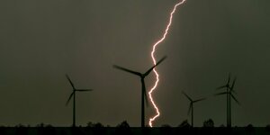 Ein Blitz erhellt fünf Windräder