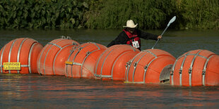 Eine Reihe von runden orangefarbenen Bojen treibt im Wasser